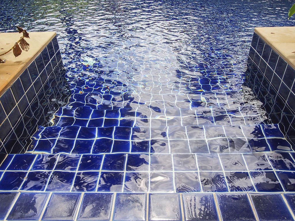Swimming pool steps with deep blue ceramic tiles and clean grout lines